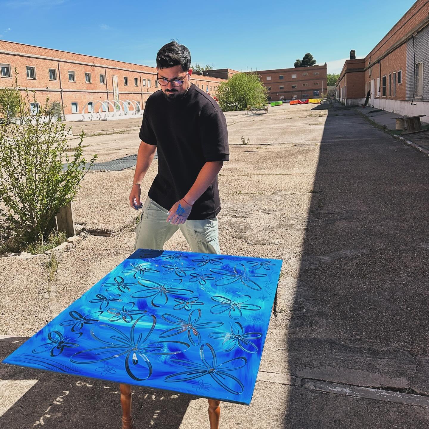 Miguel pintando sobre un cristal azul al aire libre